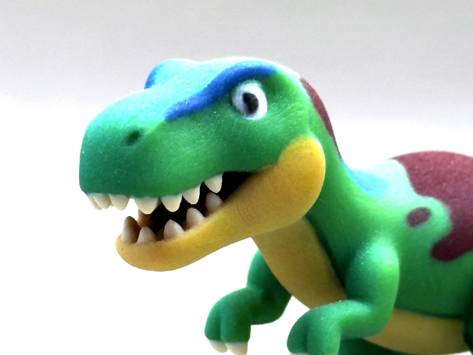 実物サンプル：恐竜のフィギュアの顔を寄って撮影した写真。歯・白目・青い眉・黄色い顎の色分けが見える